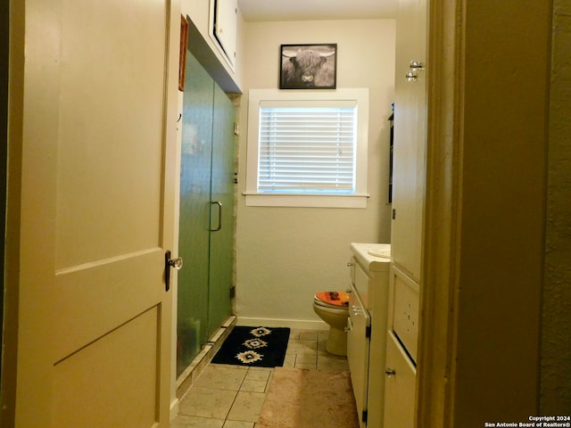 bathroom with toilet, vanity, tile patterned floors, and a shower with shower door