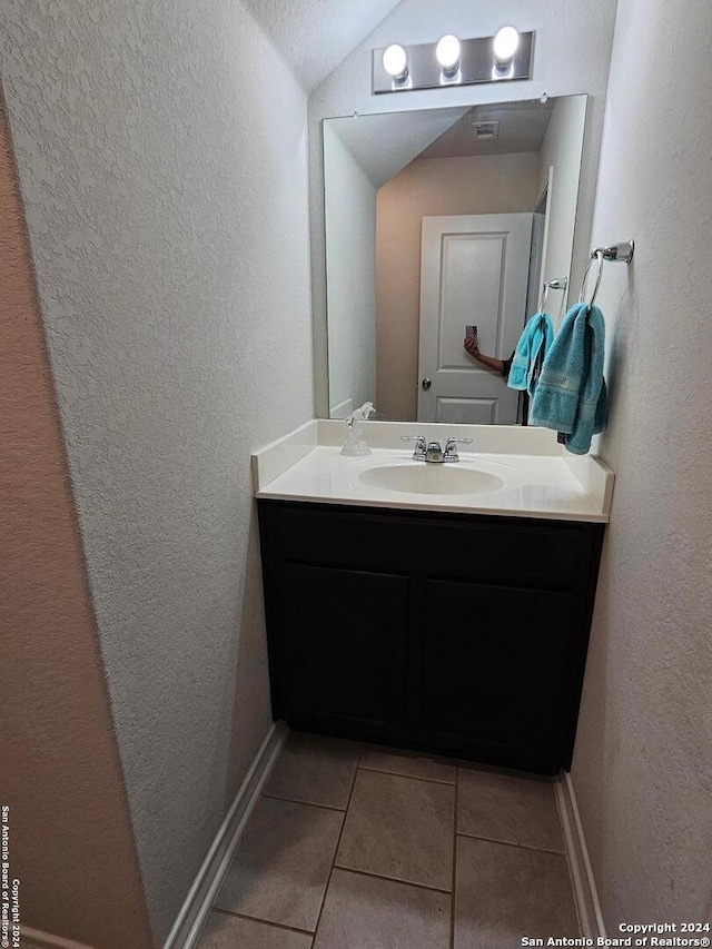 bathroom with tile patterned flooring, vanity, and vaulted ceiling