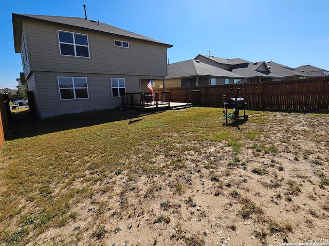 back of property featuring a deck and a lawn