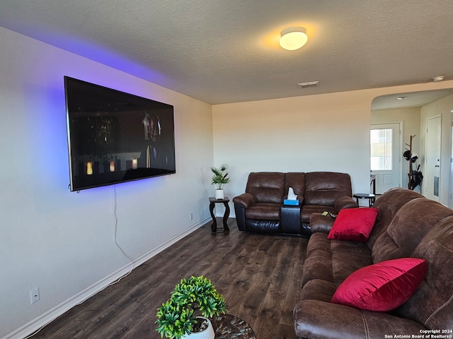 living room featuring dark wood-type flooring and a textured ceiling