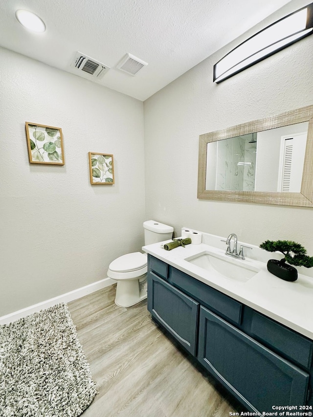 bathroom featuring wood-type flooring, vanity, a textured ceiling, and toilet