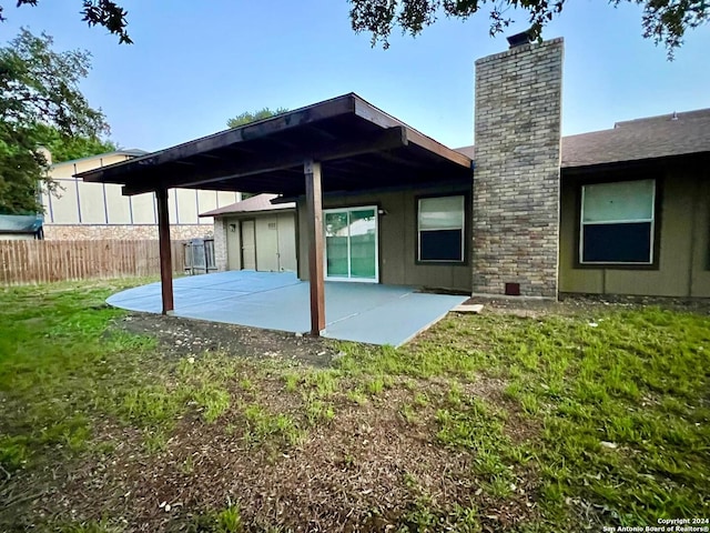 back of property with a lawn and a patio area