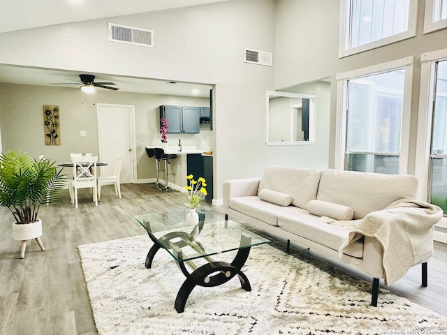 living room with high vaulted ceiling, light hardwood / wood-style flooring, and ceiling fan