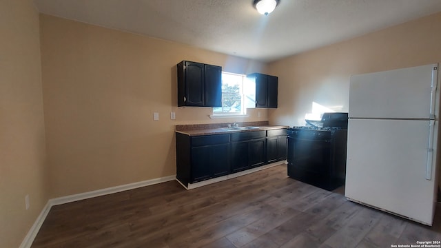 kitchen with a textured ceiling, sink, wood-type flooring, white fridge, and black electric range oven