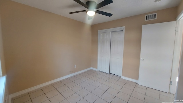 unfurnished bedroom featuring light tile patterned floors, a closet, and ceiling fan