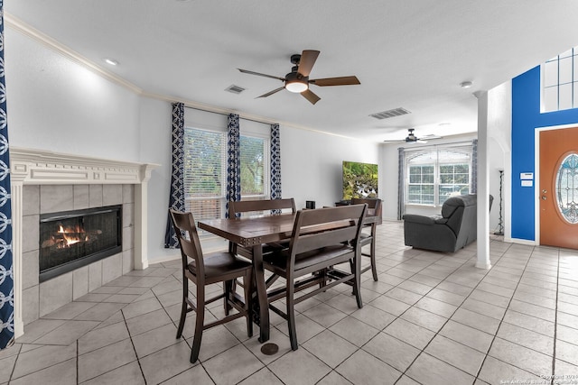 tiled dining space featuring a fireplace, plenty of natural light, crown molding, and ceiling fan