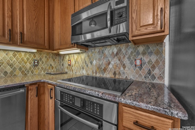 kitchen featuring appliances with stainless steel finishes, backsplash, and dark stone countertops