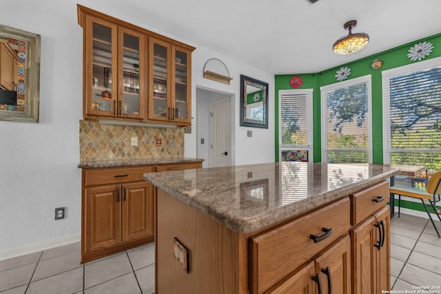 kitchen featuring light tile patterned floors, tasteful backsplash, a kitchen island, and light stone counters