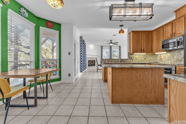 kitchen with ceiling fan, a healthy amount of sunlight, decorative light fixtures, and appliances with stainless steel finishes