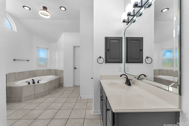 bathroom with tile patterned floors, vanity, and a relaxing tiled tub