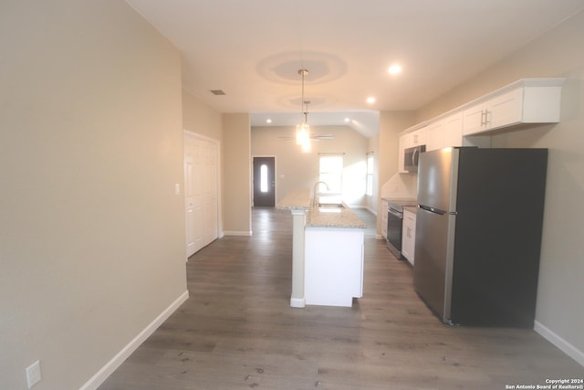 kitchen with light stone countertops, stainless steel appliances, white cabinets, dark hardwood / wood-style floors, and an island with sink