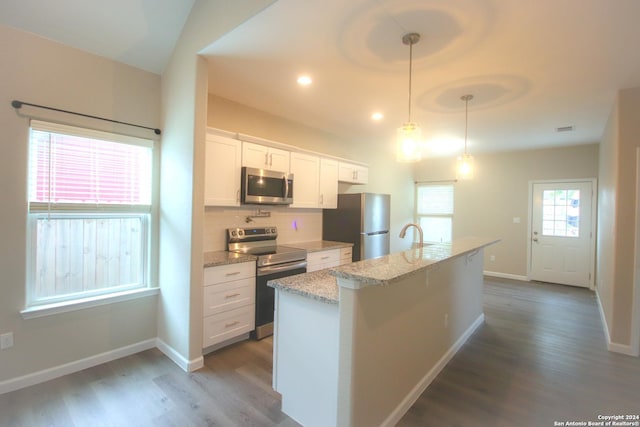 kitchen with dark wood-type flooring, a center island with sink, hanging light fixtures, appliances with stainless steel finishes, and white cabinetry