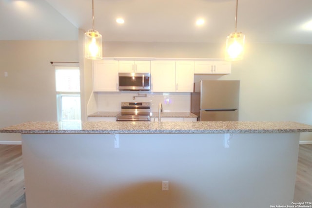 kitchen with white cabinets, hanging light fixtures, and appliances with stainless steel finishes