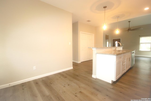 kitchen with pendant lighting, white cabinets, sink, light stone countertops, and dark hardwood / wood-style flooring