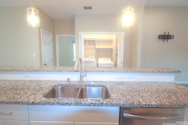 kitchen with washing machine and clothes dryer, pendant lighting, stainless steel dishwasher, and sink