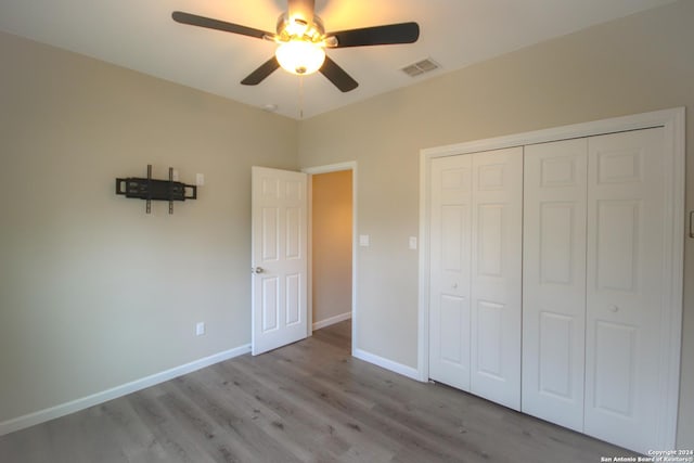 unfurnished bedroom featuring ceiling fan, a closet, and light wood-type flooring