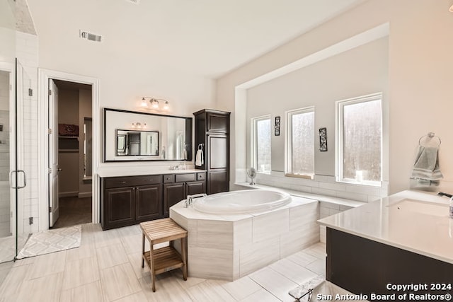 bathroom featuring plus walk in shower, vanity, and tile patterned floors