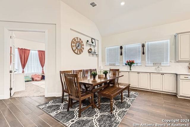 dining space featuring vaulted ceiling and dark wood-type flooring