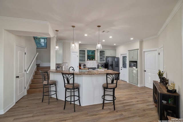 kitchen featuring backsplash, a kitchen breakfast bar, light hardwood / wood-style floors, black fridge with ice dispenser, and kitchen peninsula