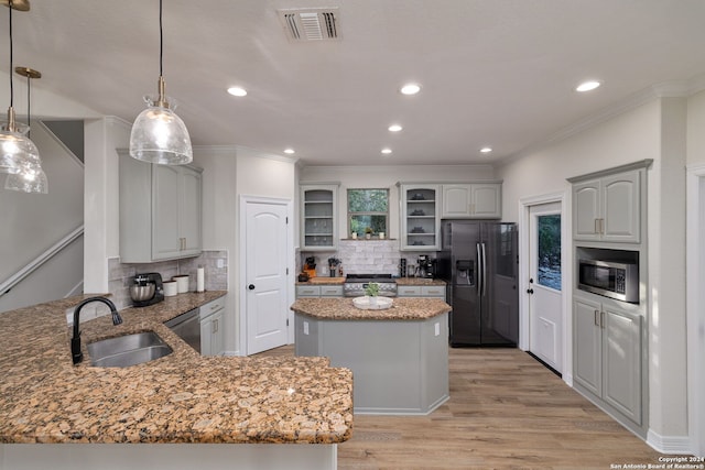 kitchen featuring a center island, sink, light hardwood / wood-style flooring, decorative backsplash, and appliances with stainless steel finishes