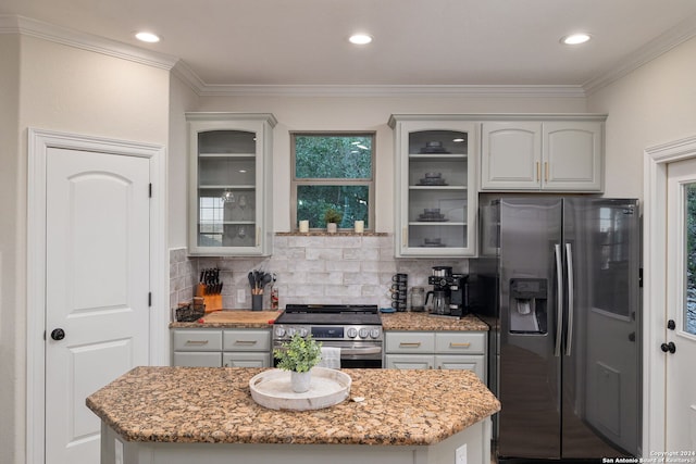 kitchen featuring decorative backsplash, light stone counters, crown molding, and appliances with stainless steel finishes