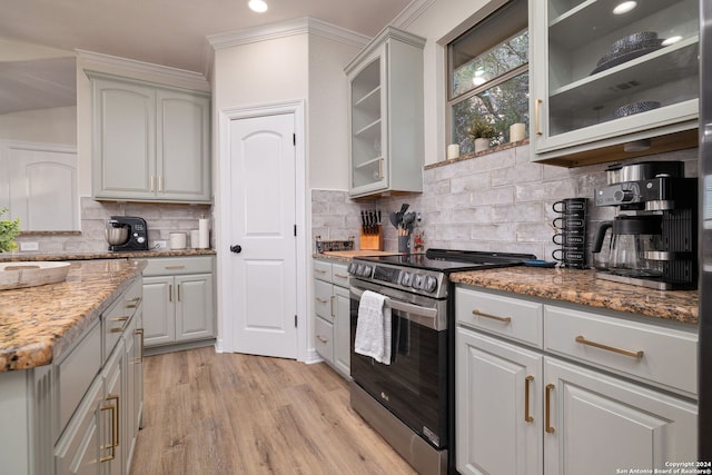 kitchen featuring crown molding, electric range, decorative backsplash, light stone countertops, and light hardwood / wood-style floors