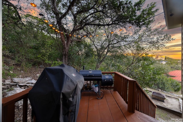 deck at dusk with area for grilling and an outdoor fire pit