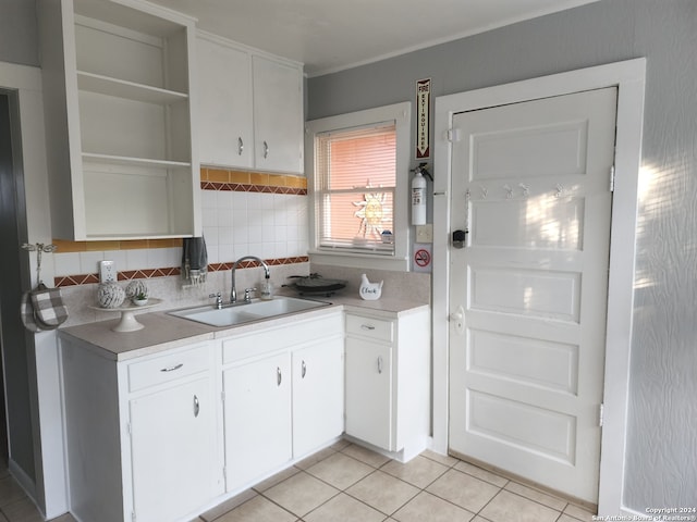 kitchen featuring decorative backsplash, sink, white cabinets, and light tile patterned floors