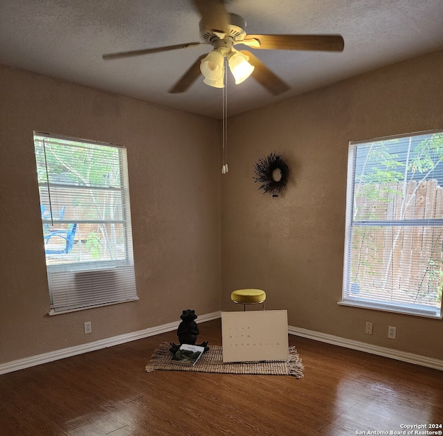 spare room featuring dark hardwood / wood-style flooring, ceiling fan, plenty of natural light, and a textured ceiling