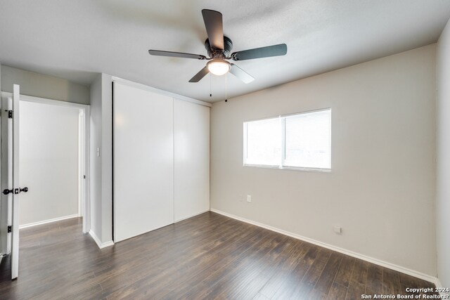 unfurnished bedroom with a closet, dark hardwood / wood-style floors, and ceiling fan