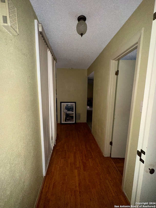 corridor featuring dark wood-type flooring and a textured ceiling