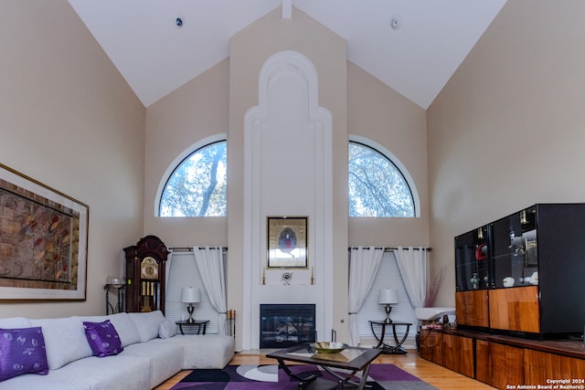 living room with a wealth of natural light, high vaulted ceiling, and light hardwood / wood-style floors