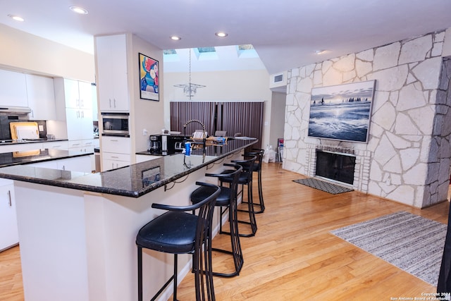 kitchen featuring a center island, white cabinetry, a fireplace, and light hardwood / wood-style flooring