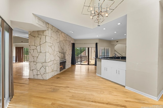 206 Bluff Holw, San Antonio, TX 78216 - interior space featuring light wood finished floors, dark countertops, a chandelier, white cabinetry, and a stone fireplace