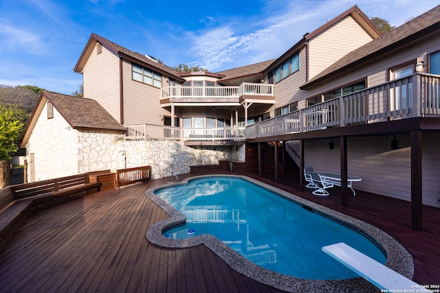 view of pool with a diving board and a deck