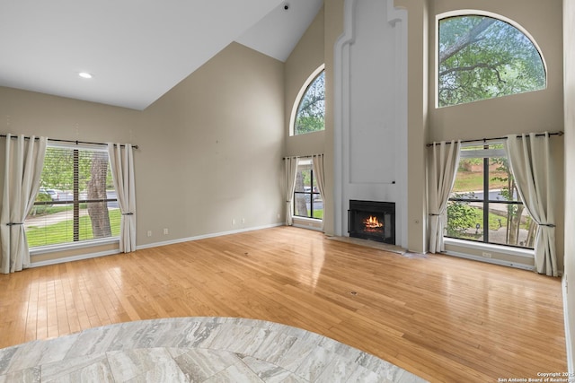 206 Bluff Holw, San Antonio, TX 78216 - unfurnished living room with high vaulted ceiling, light wood-style floors, healthy amount of natural light, a large fireplace, and baseboards