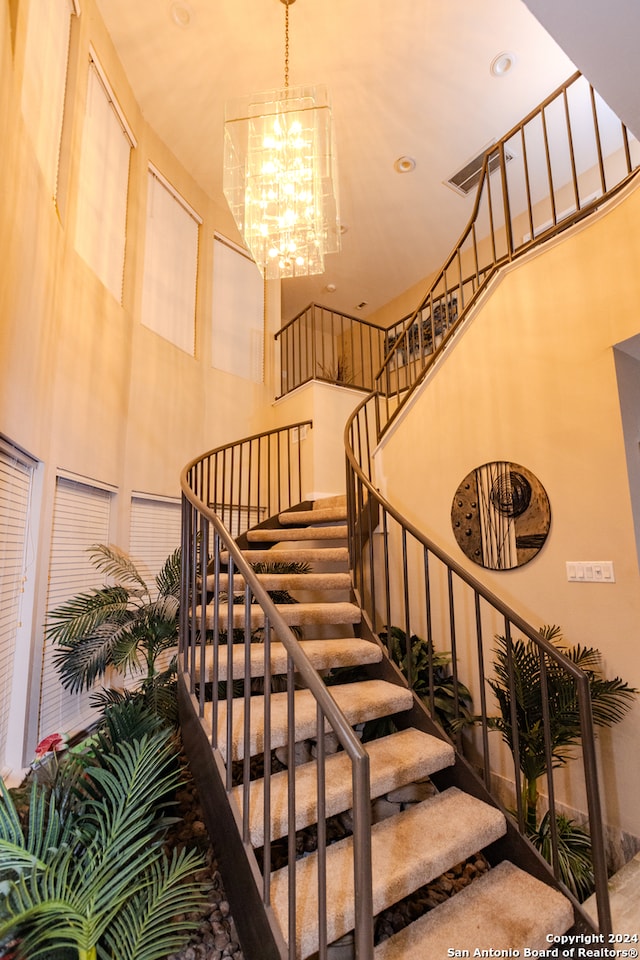 stairs featuring a towering ceiling and a chandelier