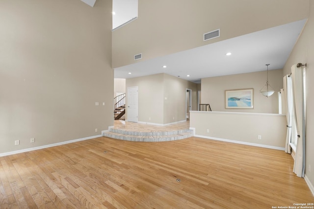 206 Bluff Holw, San Antonio, TX 78216 - unfurnished living room featuring light wood-style flooring, baseboards, stairs, a high ceiling, and recessed lighting