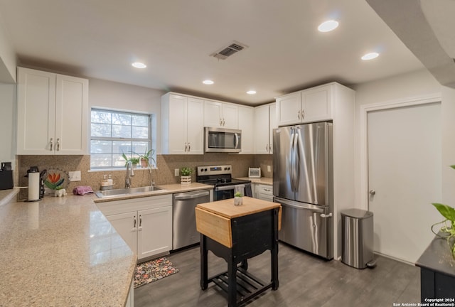 kitchen featuring white cabinetry, sink, light stone counters, dark hardwood / wood-style floors, and appliances with stainless steel finishes