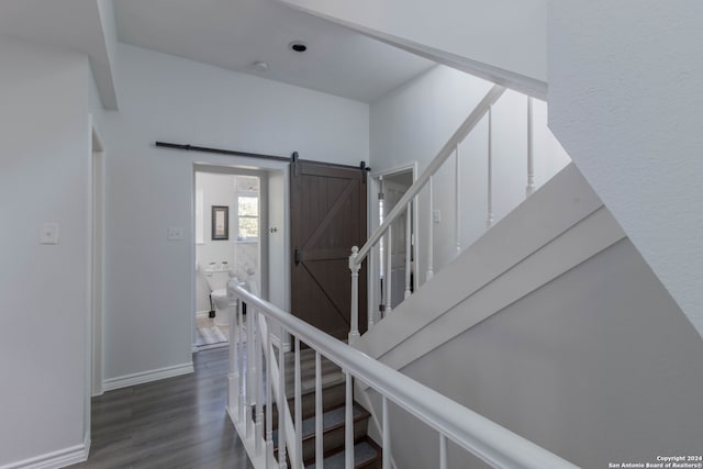 stairway featuring a barn door and hardwood / wood-style flooring