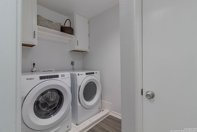 laundry area with washing machine and clothes dryer, cabinets, and hardwood / wood-style flooring