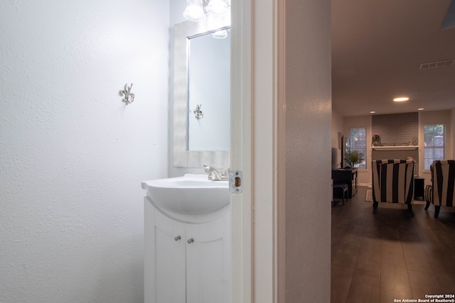 bathroom with hardwood / wood-style floors, vanity, and a brick fireplace