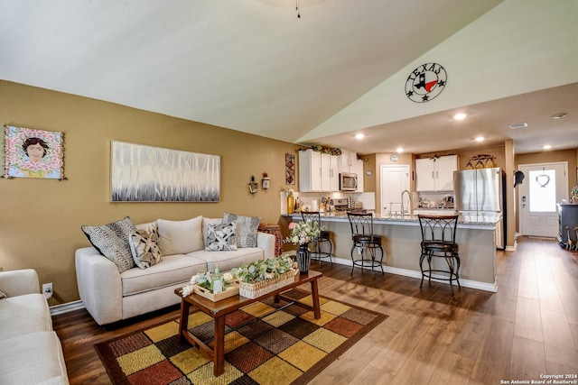 living room with hardwood / wood-style floors, lofted ceiling, and sink