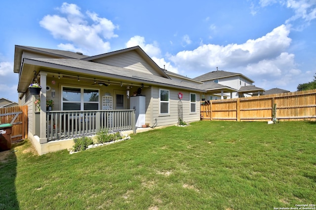 back of property featuring ceiling fan and a yard