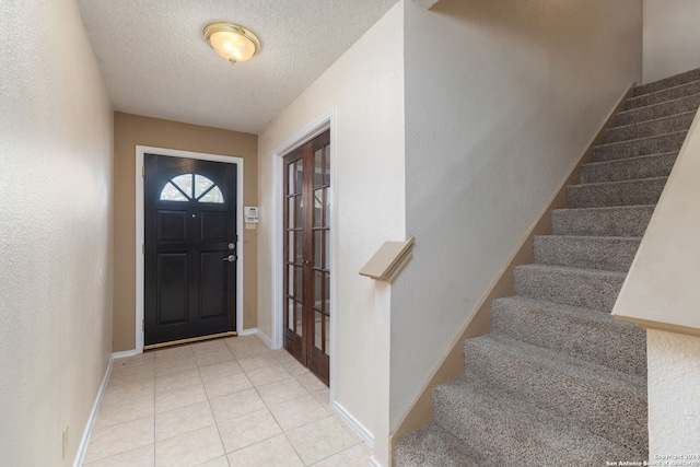 entryway with light tile patterned flooring and a textured ceiling