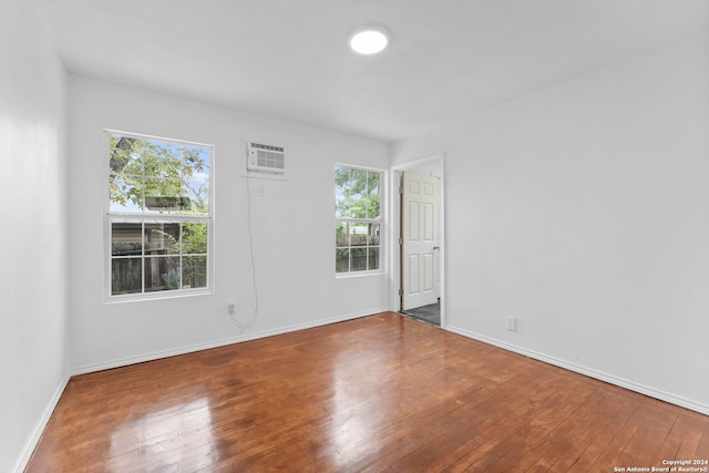 empty room featuring an AC wall unit and wood-type flooring