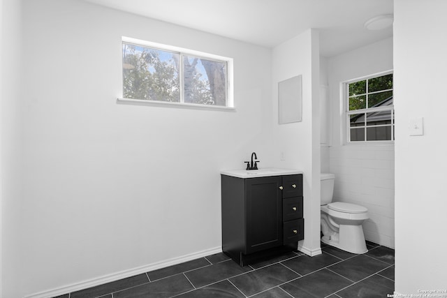 bathroom featuring tile patterned flooring, vanity, a healthy amount of sunlight, and toilet