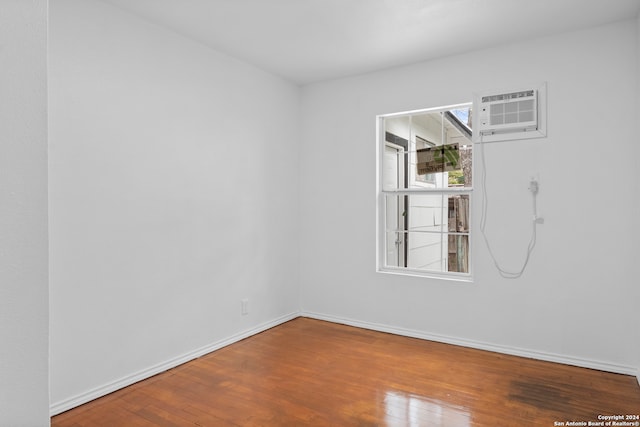 empty room featuring hardwood / wood-style flooring and an AC wall unit