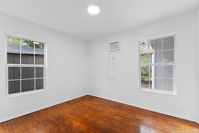 spare room featuring a wall mounted air conditioner, hardwood / wood-style flooring, and plenty of natural light