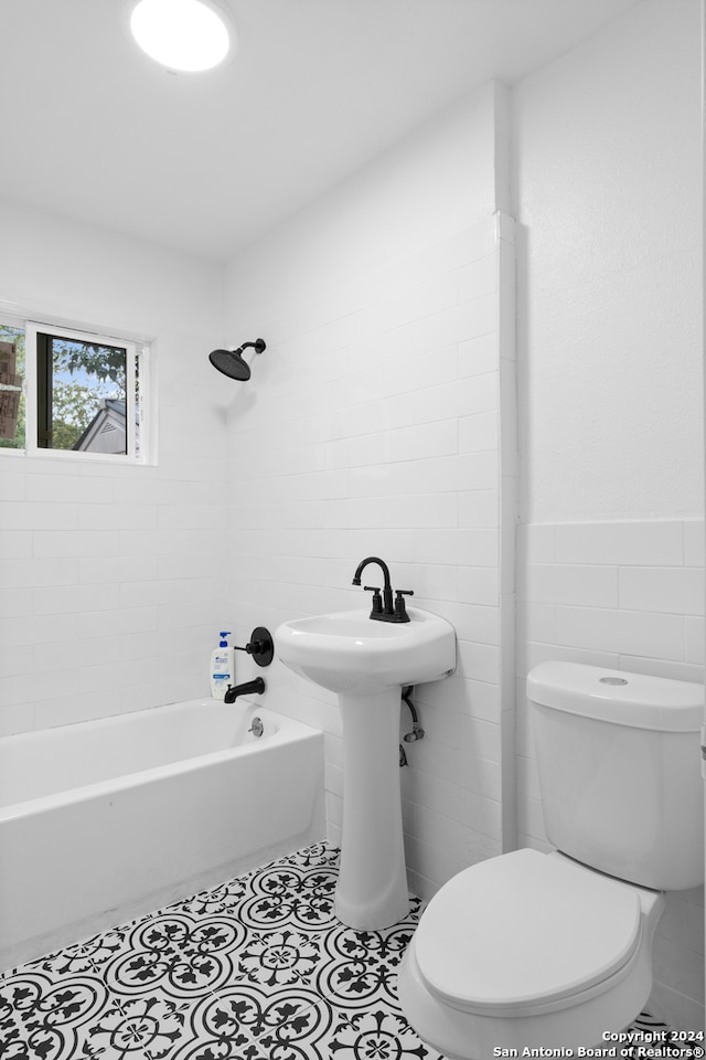 bathroom with tiled shower / bath combo, toilet, and tile walls